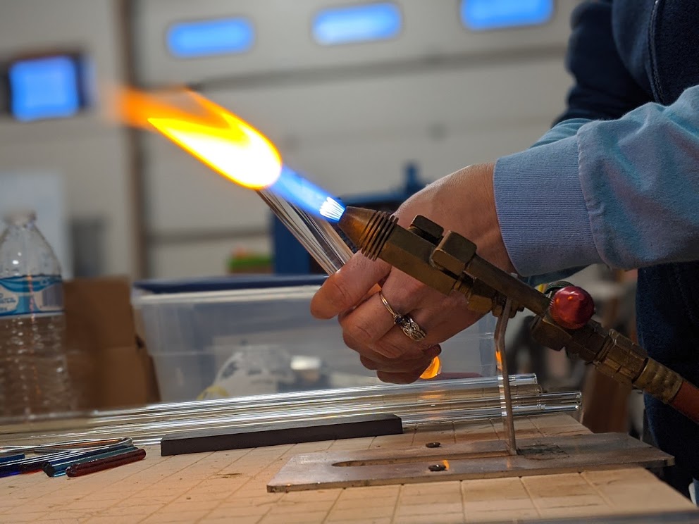 Close-up of a student's hand with two rings and the glass in-flame.